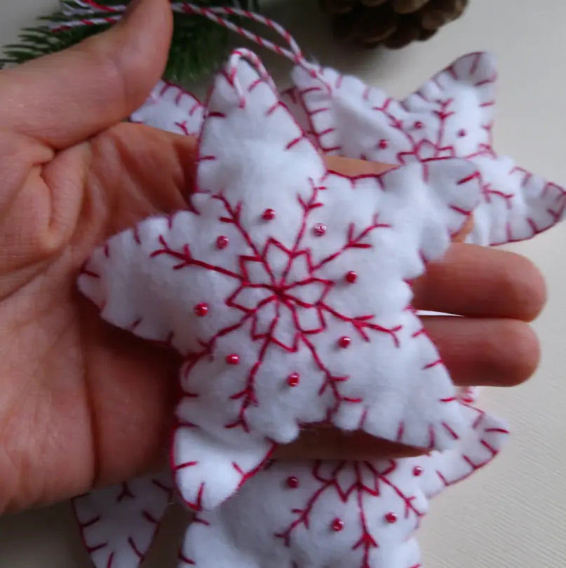 Étoile de Noël en feutrine blanche accrochée sur une branche de sapin