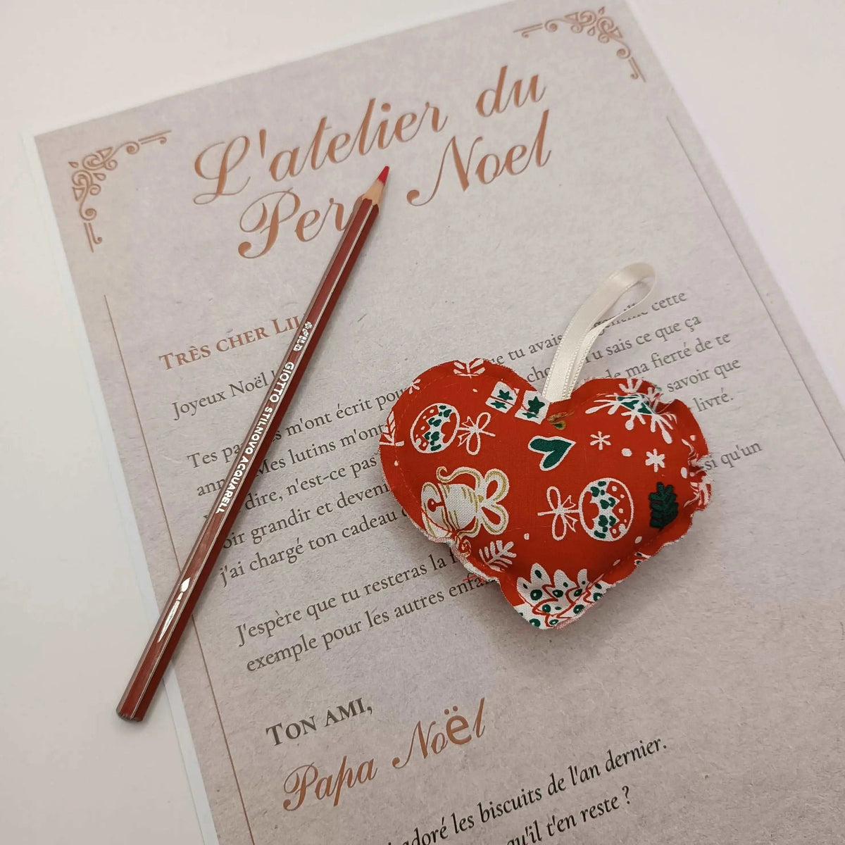 Cœur de Noël artisanal en tissu rouge accroché sur le sapin