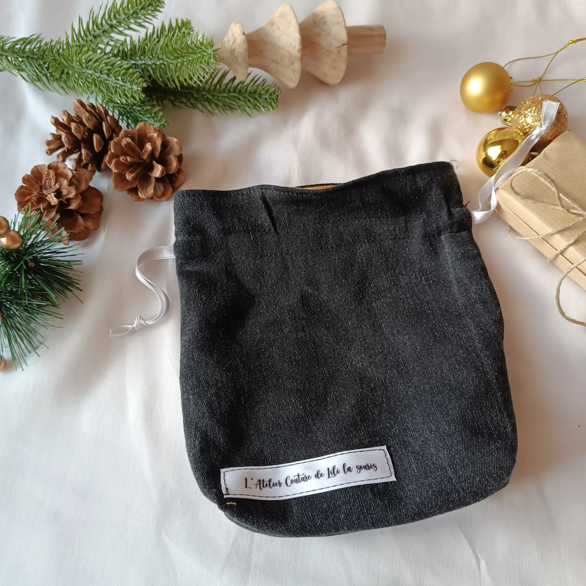 Pochon de Noël jeans noir posé avec des cadeaux emballés