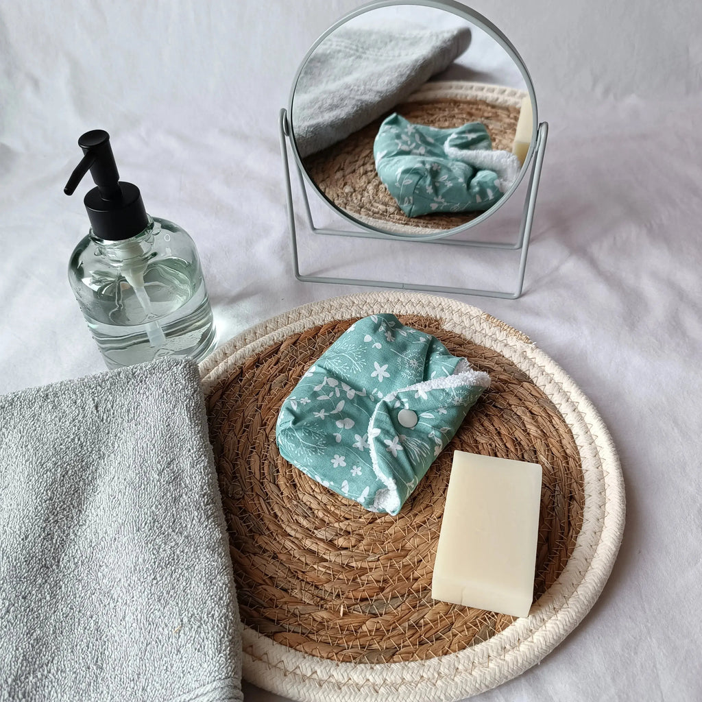 Gros plan sur l'imprimé fleuri blanc de la pochette à savon verte