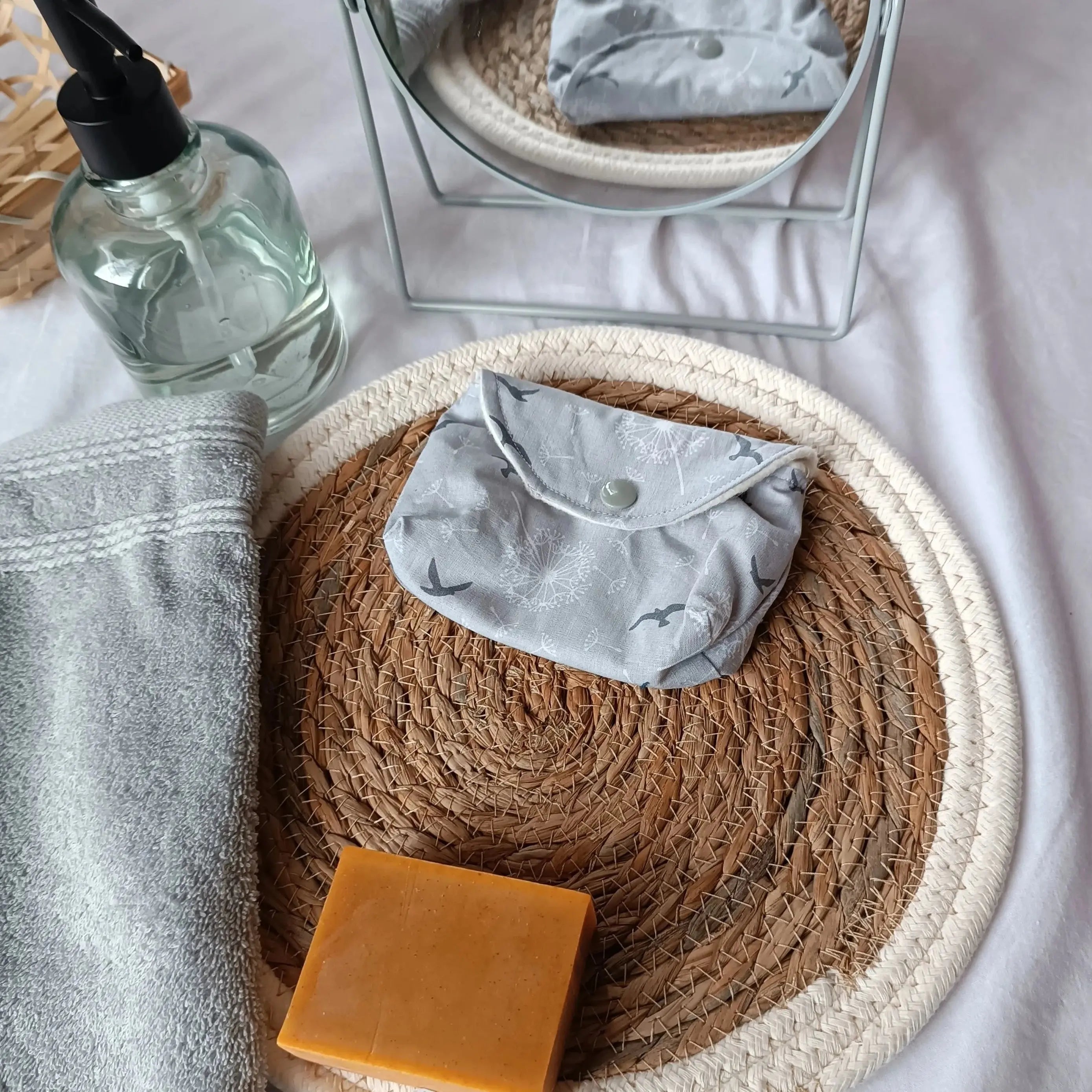 Gros plan sur l'imprimé oiseaux et fleurs de la pochette à savon grise